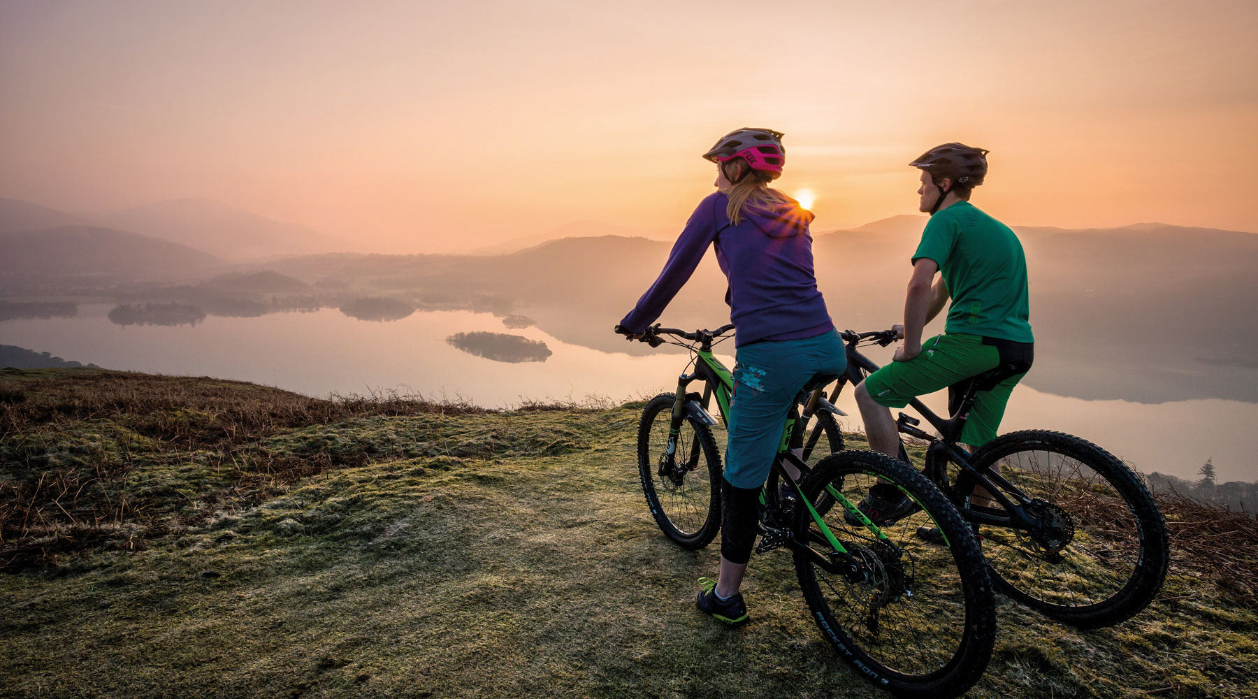 Two cyclists watching the sunrise over Derwent Water in the Lake District