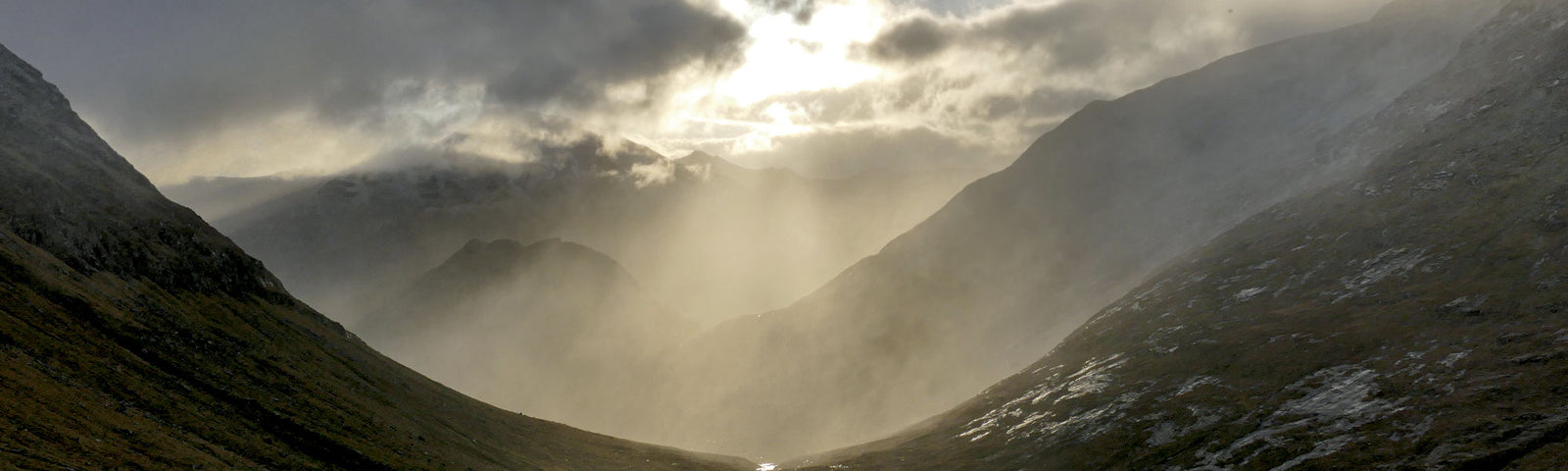 Shafts of sunlight illuminate a glen near Aonach Beag, from The Vanishing Ice by Iain Cameron